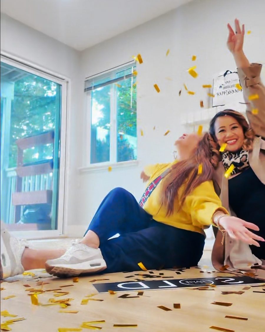 Jennifer Insisoulath and a client celebrating with confetti on the floor of their new home, next to the SOLD sign
